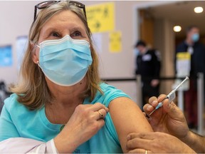 Vaccine administrator Pascal Aoude gives Brenda Alfonso her first Pfizer vaccine shot at the Dollard Civic Centre in Dollard-des-Ormeaux last March.