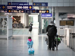 A young traveller follows her father at Montreal Trudeau airport.