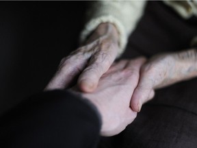 A woman holds the hand of a person with Alzheimer's.