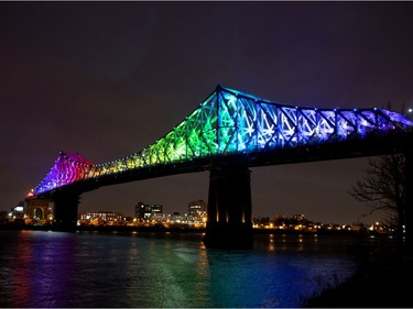 The Jacques Cartier bridge is lit up in the colours of the rainbow as a sign of solidarity and hope, seen through the city with the 'Ça va bien aller' rainbow drawings on April 2, 2020.