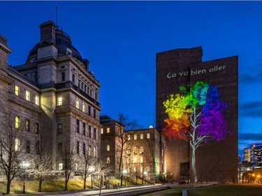 A rainbow tree is reflected against the wall of the Palais de Justice next to the Lucien Saulnier building, the temporary home of city hall, in Montreal on Wednesday April 22, 2020.
