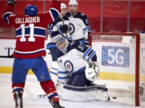 Winnipeg Jets goaltender Connor Hellebuyck watches as Canadiens' Brendan Gallagher (11) celebrates scoring against him in Montreal on March 6, 2021. Jets defenceman Dylan DeMelo (2) and Winnipeg centre Pierre-Luc Dubois (13) also look on.