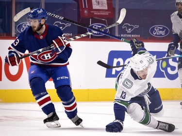 Vancouver Canucks centre Jayce Hawryluk (13) hits the ice after taking a hit from Canadiens defenceman Victor Mete (53) during NHL action in Montreal on Saturday, March 20, 2021.