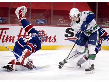 Canadiens goaltender Carey Price makes a big save against Vancouver Canucks' Brock Boeser in overtime as Montreal's Corey Perry (94) tries to stop Boeser's shot  during NHL action in Montreal on Saturday, March 20, 2021.