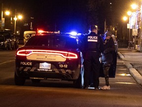 Montreal police stop to check the status of a woman walking after the start of the 8 p.m. curfew on Friday, March 12, 2021.