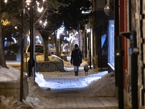 A woman walks her dog on Duluth Ave. after curfew in Montreal, on Tuesday, March 2, 2021.
