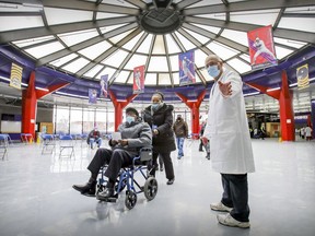Aid Luc Glaude directs senior citizens through the rotunda at the Olympic Stadium in Montreal on their way to COVID-9 vaccination appointments Friday, March 5, 2021.