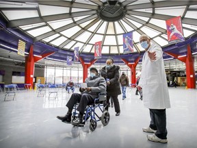 Aid Luc Glaude directs senior citizens through the rotunda at the Olympic Stadium in Montreal on their way to COVID-9 vaccination appointments on March 5, 2021.