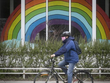 A cyclist wearing a mask rolls by a rainbow on Sherbrooke St. on May 5, 2020.