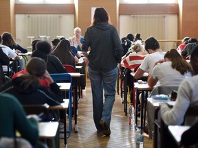 A teacher walks through a classroom during an exam.
