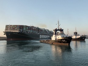 A handout picture released by the Suez Canal Authority on March 29, 2021 shows tugboats pulling the Panama-flagged MV 'Ever Given' (operated by Taiwan-based Evergreen Marine) container ship, a 400-metre- (1,300-foot-)long and 59-metre wide vessel, lodged sideways impeding traffic across Egypt's Suez Canal waterway. - Egypt's Suez Canal Authority said on March 29 the Ever Given container ship, which has been blocking the crucial waterway for nearly a week, has been "reorientated 80 percent in the right direction". Once it is refloated, it will take three and a half days to clear a traffic jam of hundreds of vessels, authorities said. Over 300 ships are currently waiting to travel through the canal.