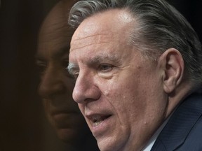Quebec Premier François Legault speaks at a news conference on the COVID-19 pandemic, Tuesday, March 16, 2021 at the legislature in Quebec City. Quebec Health Minister Christian Dube, left, is reflected in the glass.