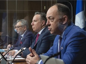 Quebec Health Minister Christian Dubé, right, responds to reporters' questions during a news conference on Tuesday, March 23, 2021 at the legislature in Quebec City. Quebec Premier François Legault, centre, and Horacio Arruda, Quebec director of National Public Health, look on.