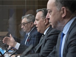 Premier François Legault is flanked by public health director Horacio Arruda, left, and Health Minister Christian Dubé on Wednesday, March 31, 2021 at the legislature in Quebec City.