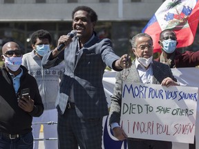 Wilner Cayo, centre, and Frantz Andre attend a demonstration outside Prime Minister Justin Trudeau's constituency office in Montreal on May 23, 2020, where they called on the government to give residency status to migrant workers as the COVID-19 pandemic continues in Canada and around the world.