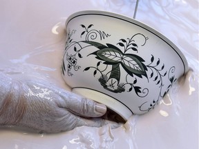 A worker immerses a porcelain vessel showing the blue crossed swords in the glaze bath in the Meissen Manufactory in Meissen, Germany, Monday, May 14, 2018. Since 1722 the blue crossed swords mark every piece of porcelain, which is produced in the manufactory of Meissen. In the 300 years and more since it was established by King Augustus the Strong in 1710, Europe's first porcelain manufactory has evolved into an international luxury and lifestyle brand.