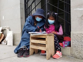 Jeanete Alanoca, who works at a cemetery, helps her daughter Neydi with her virtual classes at the Cementerio General cemetery in La Paz, Bolivia.