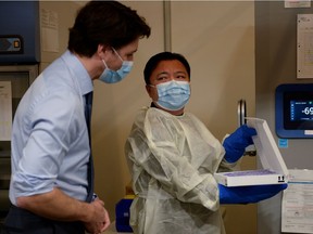 Prime Minister Justin Trudeau receives a demonstration of how the refrigeration system works while he visits a vaccination clinic at the Palais des Congrès in Montreal on March 15, 2021.