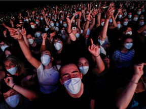 People wearing protective masks attend a concert of "Love of Lesbian" at the Palau Sant Jordi, the first massive concert since the beginning of the coronavirus disease (COVID-19) pandemic in Barcelona, Spain, on Saturday, March 27, 2021.