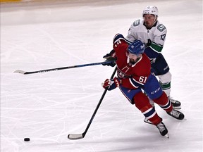 Montreal Canadiens left wing Xavier Ouellet (61) and Vancouver Canucks centre Jayce Hawryluk (13) battle the puck during the third period at Bell Centre March 19, 2021.