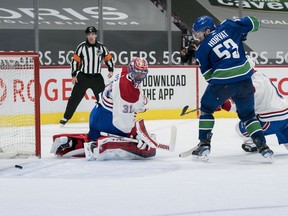 Canucks forward Bo Horvat and Canadiens goalie Carey Price track a rebound during third-period action Monday night at Rogers Arena in Vancouver.