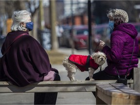 To ward off and to prevent spreading the COVID-19 coronavirus, Anna Fuerstenberg (left) and Lara Shelton, holding her dog Sparky, wear masks outside a café in Montreal Sunday, March 21, 2021.