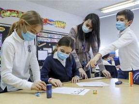 Students Mathilde Benjamin, left, and twins Béatrice and Charles O'Doherty wear masks while receiving help from resource teacher Christine Valerio at John Caboto Academy in Montreal on March 8, 2021. Most youngsters took mask-wearing in stride last year. They accepted it as a necessity to keep themselves and others safe — and to keep schools open.