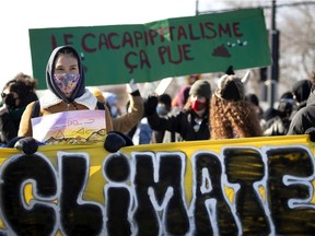 Marian Imak carries a banner with a coalition of youth and environmental groups as they hold a climate change march in Montreal, on Friday, March 19, 2021.