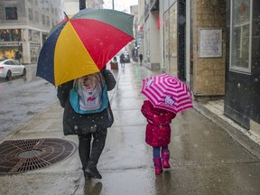 A mother and daughter had their umbrellas out while walking on Sainte-Catherine St. on a snowy morning in Montreal Thursday April 1, 2021.