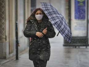 Farah Hamam shelters under an umbrella as she walks up Peel St. on a snowy morning in Montreal Thursday April 1, 2021.