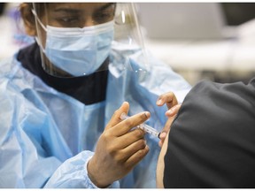 Navpreet Kaur injects a Montrealer with an AstraZeneca vaccine at the Bill Durnan arena.