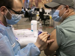 Joseph Lapuz receives his AstraZeneca vaccine from Mouhanad Alnirabiah on Thursday April 8, 2021 at the Bill Durnan arena in Côte-des-Neiges.