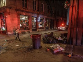 A woman walks by damage on St-Paul St. W. that was made when a crowd of at least several hundred people gathered in Old Montreal, chanting and shooting off fireworks to protest the return to an 8 p.m. curfew in Montreal.