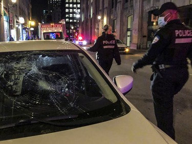 A police officer looks at damage to a car on rue Notre-Dame West in Old Montreal on April 11, 2021.