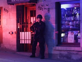 A Montreal police officer stands against a building in Old Montreal April 12, 2021. Protesters against COVID-19 restrictions  were out after the 8:00 p.m. curfew.
