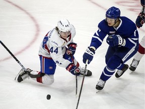 Laval Rocket's Cole Caufield, left, fights for control of the puck with Toronto Marlies' Teemu Kivihalme at Toronto's Coca-Cola Coliseum on April 9, 2021.