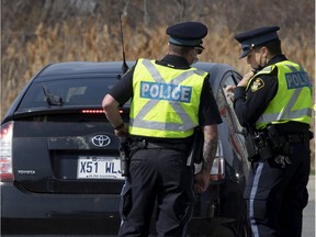 OPP verify the identification and purpose of a Quebec motorist as they man road checks on Highway 401 as the Quebec Ontario border is closed due to COVID-19 pandemic health rules, on Monday, April 19, 2021.