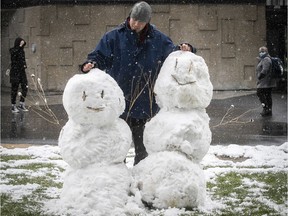 Christopher Fafard looks at his completed pair of snowmen at Champ-de-Mars metro station in front of the CHUM hospital on Wednesday April 21, 2021 during the COVID-19 pandemic. Fafard decided to make the snowmen to put a smile on health care workers who will look out the window of the hospital.