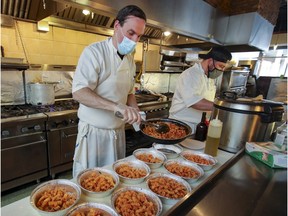 Vivaldi restaurant chef and co-owner Steve Droulis, left, and chef Spiro Angionicolaitis prepare 25 meals for students at nearby Terry Fox Elementary School in Pierrefonds last Thursday. Vivaldi is one of a group of restaurants taking part in Feed Our Future, a new West Island Facebook group initiative whereby local restaurants partner with the Lester B. Pearson School Board to provide meals to students in need.