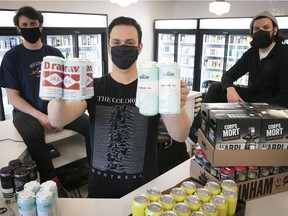 Fred Masse holds four packs of beer with co-owners Sam Kirk, left, and Kevin Demers, at the Dépanneur Bière Froide Cold Beer, on April 23, 2021, during the COVID-19 pandemic.