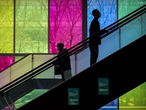 A man riding the escalator up to get his COVID-19 vaccination passes a woman heading down after receiving her shot at the Palais des Congrès in Montreal April 27, 2021.