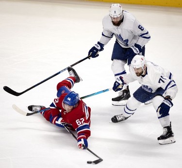 Habs left wing Artturi Lehkonen plays the puck up the ice after taking a hit from Toronto Maple Leafs defenseman Jake Muzzin and left wing Nick Foligno during first-period action in Montreal on Wednesday, April 28, 2021.