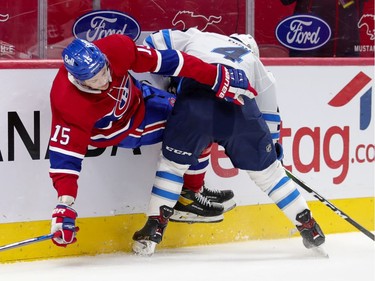 Canadiens' Jesperi Kotkaniemi is checked by Jets defenceman Neal Pionk during first-period action at the Bell Centre on Thursday night.