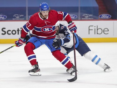 Josh Anderson controls the puck with one hand while holding off Winnipeg Jets' Derek Forbort during first-period action at the Bell Centre in Montreal on Thursday, April 8, 2021.
