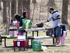 A family keeps their protective face masks as they prepare for a family picnic is a quiet corner of Mount Royal Park in Montreal on Sunday, April 11, 2021.