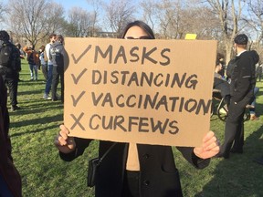 Maggie, a protester at Jeanne-Mance Park, holds a poster expressing her opposition to curfews during a protest on Sunday, April 18, 2021.