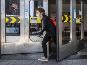 A mask-wearing woman makes a dash for a waiting bus while exiting the Guy-Concordia Metro station during continuing pandemic in Montreal Wednesday April 7, 2021.