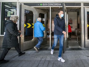 Mask-wearing transit users pass through the doors of the Guy-Concordia Metro station on Guy St. in April 2021.