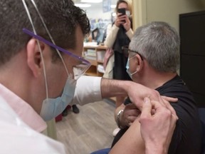 A pharmacist administers the Moderna vaccine to Quebec public health director Dr. Horacio Arruda at a pharmacy in St-Eustache on Monday, April 19, 2021.