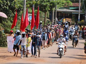 This handout photo taken and released by Dawei Watch on Saturday, April 10, 2021, shows protesters holding flags as they march in a demonstration against the military coup in Launglone township in Myanmar's Dawei district.